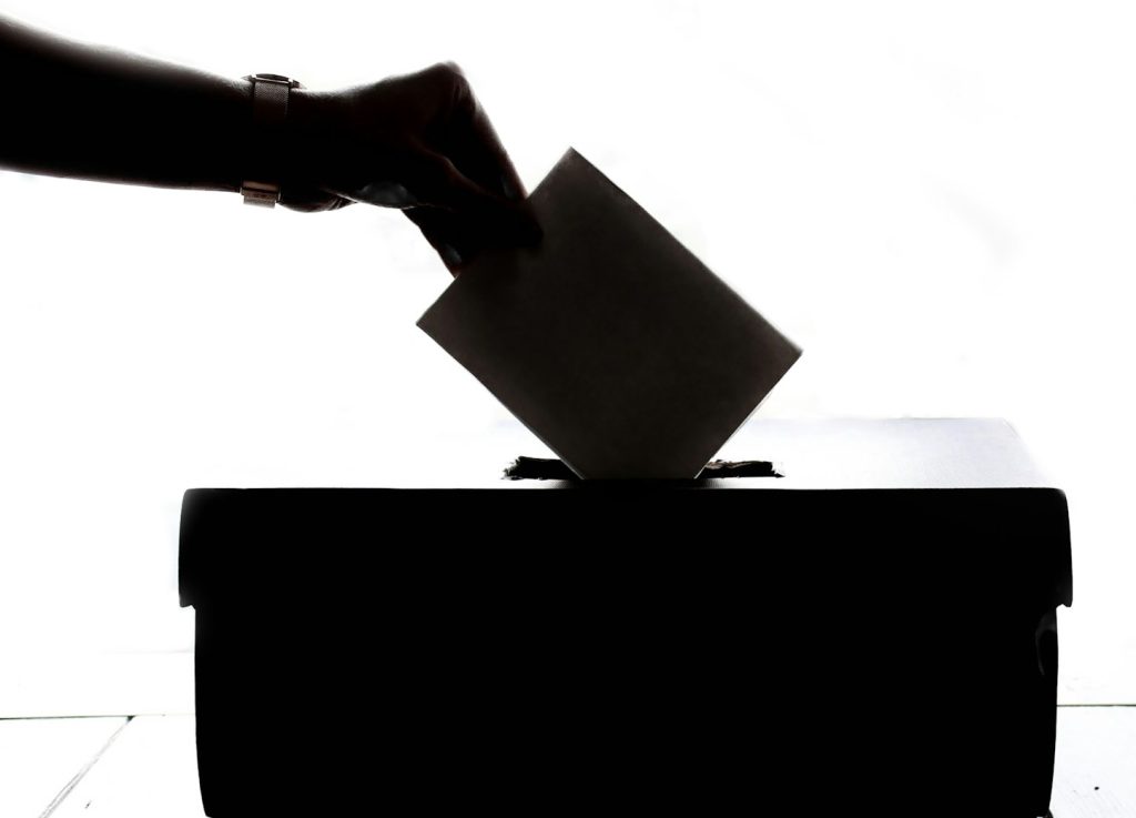 a person is casting a vote into a box